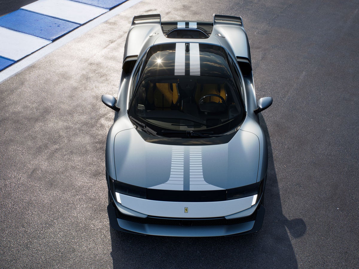 Aerial view of a gray Ferrari with white racing stripes on an asphalt track.
