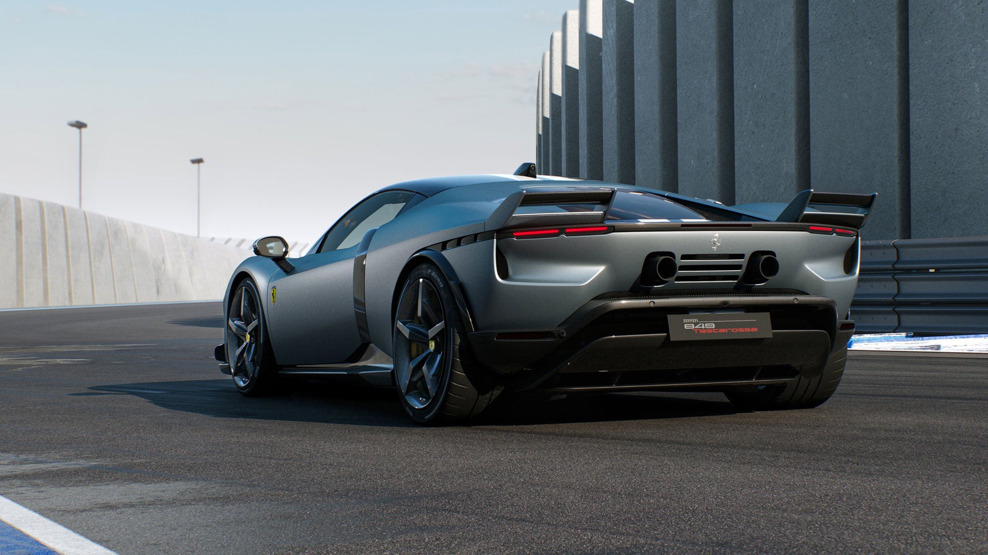 Rear view of a sleek metallic gray sports car with a large spoiler and dual exhaust pipes on a racetrack.