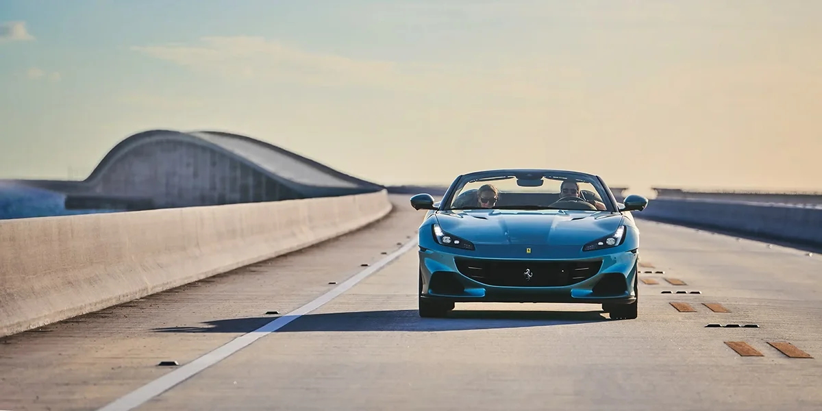 Ferrari Portofino M side profile at city waterfront during sunset