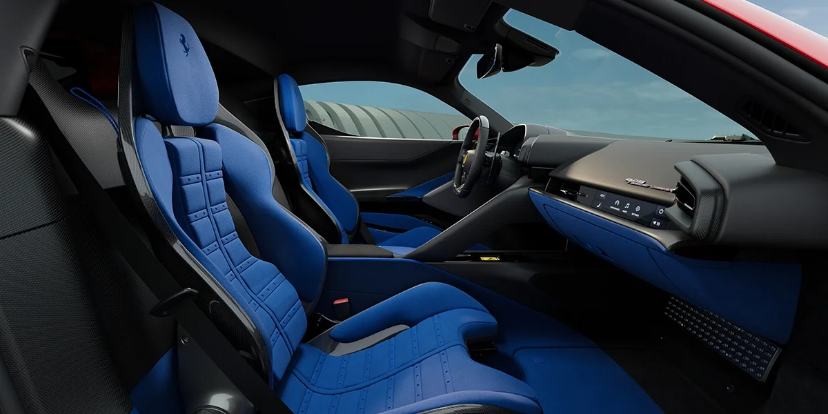 Interior view of the Ferrari 849 Testarossa showing blue sport bucket seats with black and carbon fiber trim.