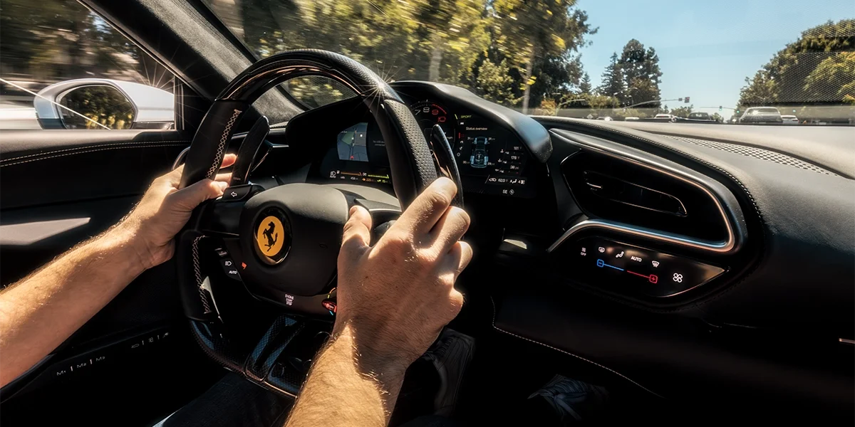 Driver's perspective inside Ferrari 296 GTS showing steering wheel and hybrid display